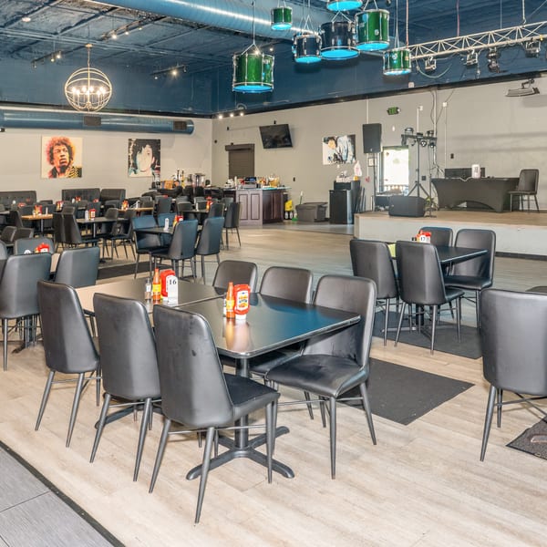 Spacious restaurant dining area with black tables and chairs, a stage, and music-themed decor.