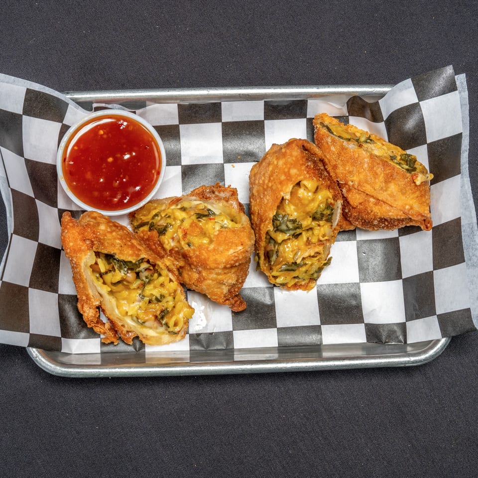 Four crispy egg rolls filled with macaroni and cheese, spinach, and beans, served with sweet chili sauce.