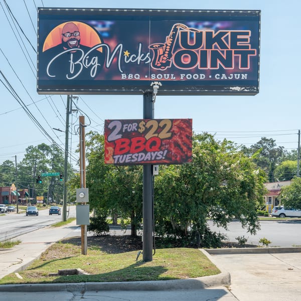 A roadside sign for Big Nick's Juke Joint, advertising BBQ, Soul Food, and Cajun cuisine, with a "2 for $22 BBQ Tuesdays!" special.